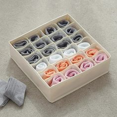 an open box filled with socks on the floor next to a pair of gray socks