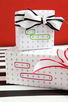 two wrapped gift boxes sitting on top of each other with black and white ribbons tied around them