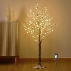 a lighted tree next to a cell phone on a stand in front of a wall