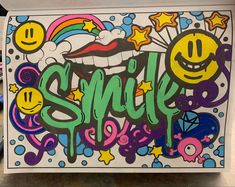 the word smile is painted on top of a box with smiley faces and stars around it