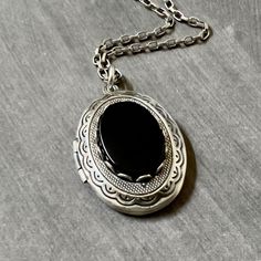 Antique Silver Onyx Locket Necklace....  This locket necklace is beautiful!  The locket is made of brass and is antique silver plated.  To the center of the locket, I added a flat top oval black onyx cabochon that sits in an antiqued silver brass setting. The high quality chain has soldered links and is non tarnish.  The chain closes with a lobster claw clasp.         Locket - 29mm height x 22mm width approximately Interior photo area - 20mm x 15mm wide approximately Chain - 24 inches long This sweet vintage style locket would be perfect to add photos of relatives, friends or pets. Your locket necklace will come to you gift wrapped!   More beautiful lockets!  https://www.etsy.com/shop/dayslonggone/?etsrc=sdt&section_id=6107145 Nature and vintage inspired necklaces!  https://www.etsy.com/sh Black Locket, Photo Area, Locket Necklace Vintage, Interior Photo, Necklace Vintage, Locket Necklace, Mother's Day Gift, Black Onyx, Lobster Claw