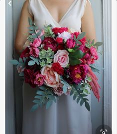 a woman in a white dress holding a large bouquet of pink flowers and greenery