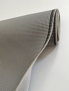 a black and white checkered tie hanging on the wall next to a white wall