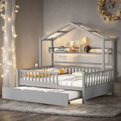 a child's bed with a white wooden frame and mattress underneath it in a room decorated with string lights