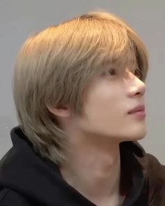 a young man with blonde hair wearing a black hoodie and looking off to the side