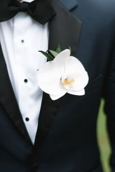 a man in a tuxedo with a white flower on his lapel coat