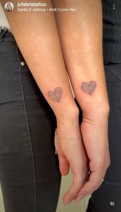 two people holding hands with tattoos on their arms and one has a heart in the middle