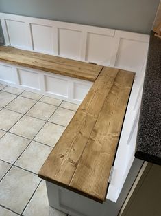 a wooden bench sitting in the middle of a kitchen next to a counter top and tile floor