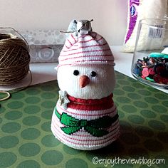 a knitted snowman sitting on top of a table next to some yarn balls