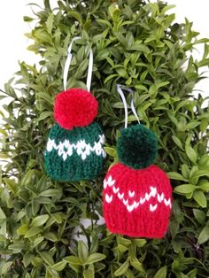 two knitted christmas hats hanging from a tree