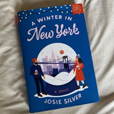 a book about winter in new york is laying on a bed