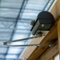 a security camera mounted to the side of a wooden door with metal bars on it