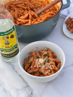 two bowls filled with pasta next to a bottle of wine