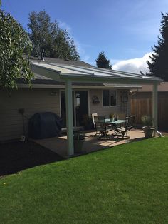 a back yard with a patio and table in the foreground on a sunny day