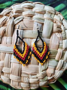 a pair of beaded earrings sitting on top of a basket