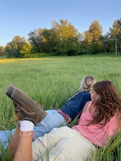 two people laying in the grass with their feet on each other