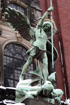 a statue on top of a building with a cross in it's hands and wings