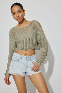 a young woman posing for the camera wearing shorts and a cropped top with long sleeves