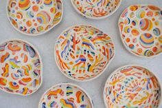 six colorful bowls with designs on them sitting on a table