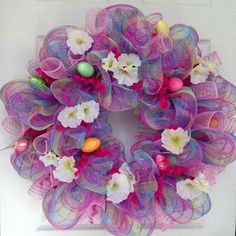 a purple wreath with white flowers and eggs in the center on a door hanger