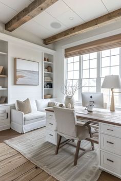 a home office with white furniture and wood beams on the ceiling, along with a large window