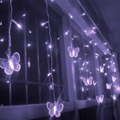 some lights that are on the side of a building with butterflies hanging from it's sides