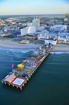 an aerial view of a pier in the middle of the ocean with buildings around it