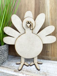 a wooden turkey standing next to a potted plant