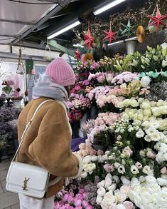 a woman looking at flowers in a flower shop