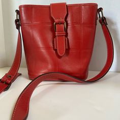 This Gorgeous Genuine Leather Bag Was Made In Italy By Carla Machi. It Is In Excellent Preowed Condition! The Bucket Bag Is A Bright, Bold Red With Large Grid Lines Debossed Into Leather Exterior And And Cream Colored Stitching With Xxxxxx On The Side Tabs To Hold The Strap Buckle. Bucket Closure With Magnetic Snap Closure To Keep Your Belongings Secure The Purse Bag Is Divided Into 3 Inner Compartments - The Center Secured With A Zipper For Your Wallet There Is A 4th Compartment That Is Zippered For Your Smaller Valuables, And Has The Shiny Gold Carla Marchi Logo And A Tag That States It Is Genuine Leather And Made In Italy. This Beautiful Purse Has A Textured Brown Fabric That Complem Red Bucket Satchel For Shopping, Elegant Red Bucket Bag For Everyday Use, Red Formal Bucket Bag With Adjustable Strap, Elegant Red Bucket Bag For Everyday, Formal Red Bucket Bag With Adjustable Strap, Elegant Red Everyday Bucket Bag, Red Square Bucket Bag For Daily Use, Red Leather Bucket Bag, Red Leather Pouch Shoulder Bag