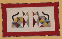 two cats are depicted on a quilted wall hanging