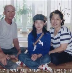 an older man and woman sitting on the floor next to each other in front of a window