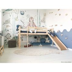 a child's bedroom with a bunk bed and slide in the middle, under a mural