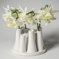 three white vases with flowers in them