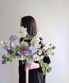 a woman holding a bouquet of flowers in her hands and wearing a black shirt with long sleeves