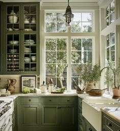 a kitchen filled with lots of green cupboards and counter top space next to a window