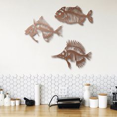 three metal fish mounted to the wall above a kitchen counter