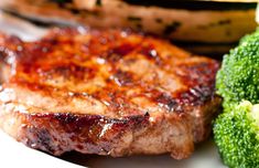 a steak and broccoli on a plate with some type of meat in the background