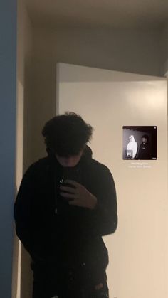 a man standing in front of a mirror looking at his cell phone