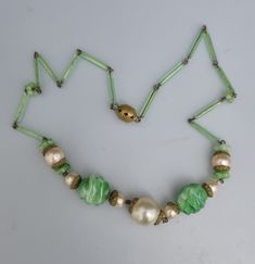 "An early piece. Very special. Peking Glass, depicting Jade gemstone. 15\" in length so more of a choker. Two central drizzle/stepped/ridged beads, flanked with faux pearls with caplets. One caplets missing on the small pearl. Bugle beads forming the 'chain'. A couple of the bugle beads have nicks towards the openings, one closest to clasp and the other 3 beads along from the centre. Ornate filigree ball clasp." Vintage Czech Glass Beaded Necklace, Vintage Adjustable Faceted Beads, Vintage Beads For Jewelry Making, Green Round Beaded Jewelry With Bead Caps, Green Beads With Bead Caps For Jewelry Making, Adjustable Vintage Beads For Jewelry Making, Vintage Necklace With Bead Caps And Round Beads, Vintage Necklaces With Round Beads And Bead Caps, Vintage Beaded Necklace With Bead Caps