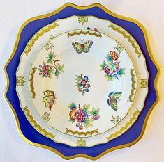 an ornate blue and gold plate with flowers on the rim is displayed against a white background