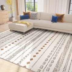 a white couch sitting on top of a wooden floor next to a large area rug