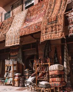 an outdoor market with lots of rugs and other items on display in front of it