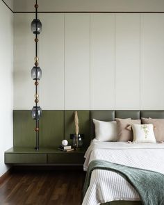 a bedroom with white and green walls, wood flooring and a large headboard