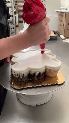 a person is decorating cupcakes with icing on a cake platter