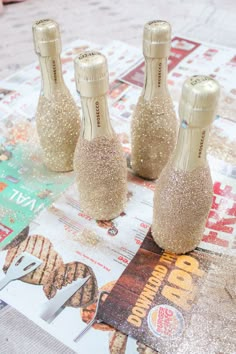 three champagne bottles sitting on top of a table covered in glitter and gold flakes