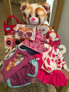 a teddy bear sitting on top of a wooden chair filled with clothing and other items