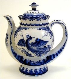 a blue and white teapot with a bird on the top, sitting in front of a white background