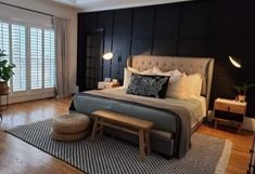 a bedroom with black walls and wood flooring has a large bed in the center