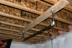 an unfinished room with wooden walls and exposed pipes on the ceiling, along with wood framing